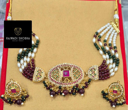 Jadau necklace featuring pearls and green stones, showcasing intricate craftsmanship and elegant design.